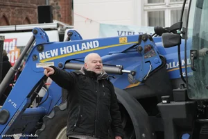 Eine Person gestikuliert vor einem Traktor.