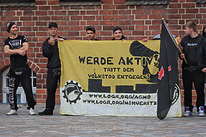 Schwarz gekleidete Personen halten ein Banner mit der Aufschrift "Werde aktiv! Tritt dem Volkstod entgegen".