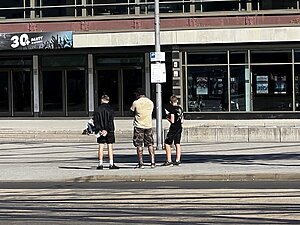 Drei Personen verteilen Flyer vor einer Halle